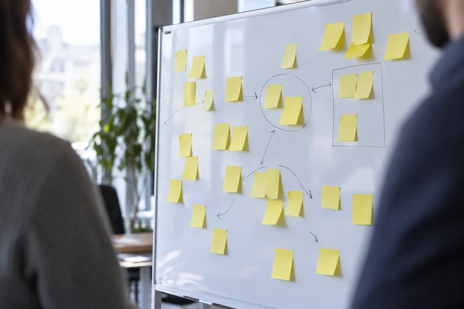 Tableau blanc couvert de post-it jaunes lors d'un atelier d'équipe, silhouette floue en arrière-plan